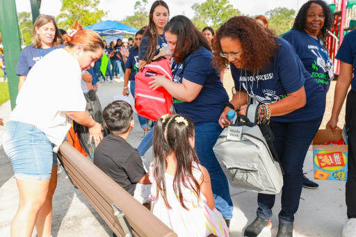adults handing children sitting on a bench backpacks