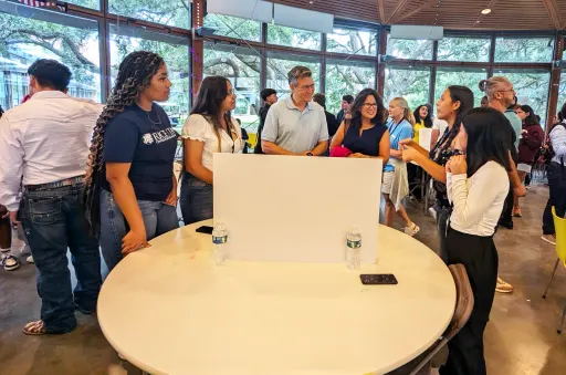 group of people gathered around a student's table presentation