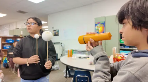 students demonstrating an eclipse with foam balls and a flashlight