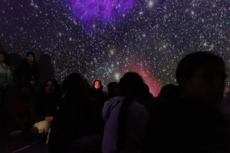 students gathered under a projection of stars