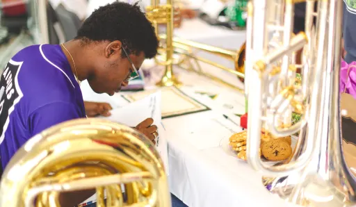 Boy hunched over at a table with various brass instruments