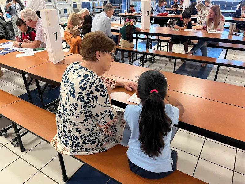woman sitting next to young student playing bingo