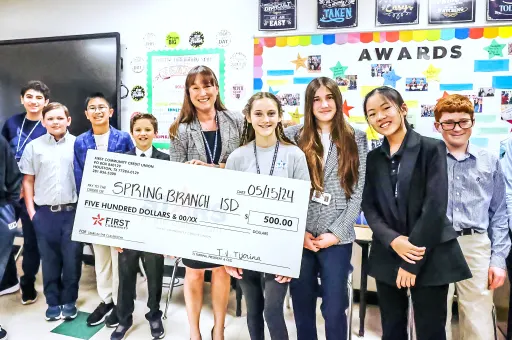 group of students and teacher standing behind large novelty check of $500 addressed to Spring Branch ISD