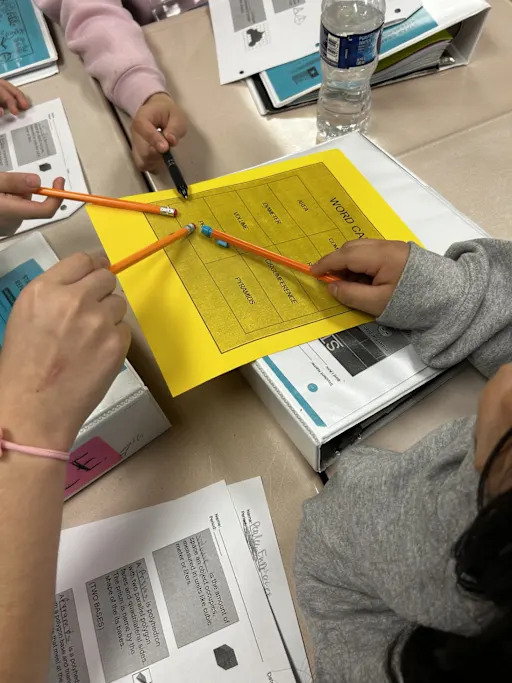 students pointing at a worksheet with pencils