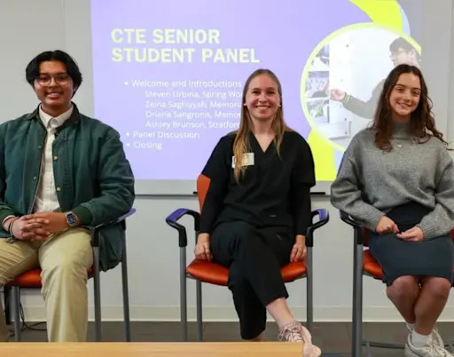 three students sitting in front of a projected screen reading "CTE Senior Student Panel"