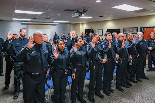 group of new police officers raising their right hand getting sworn in