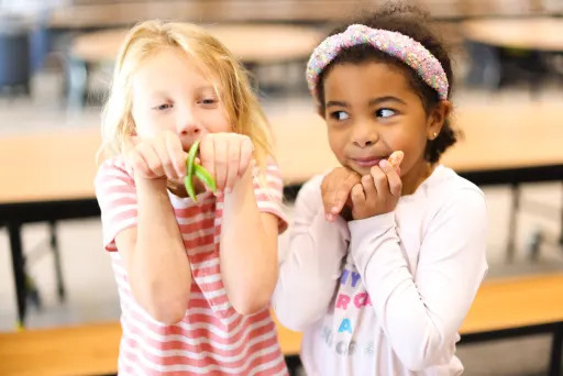 two young girls holding pea pods