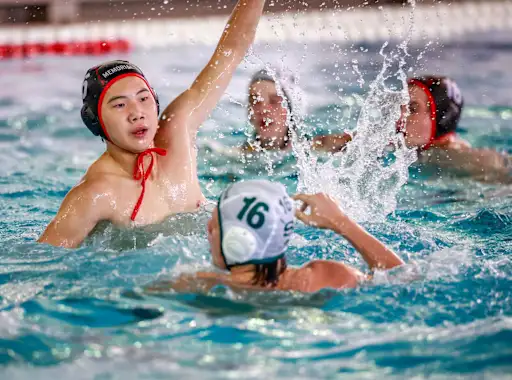 a Memorial high school water polo player leaps up in the water in front of a stratford player