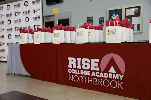 Gift bags on a table labeled "RISE College Academy Northbrook"