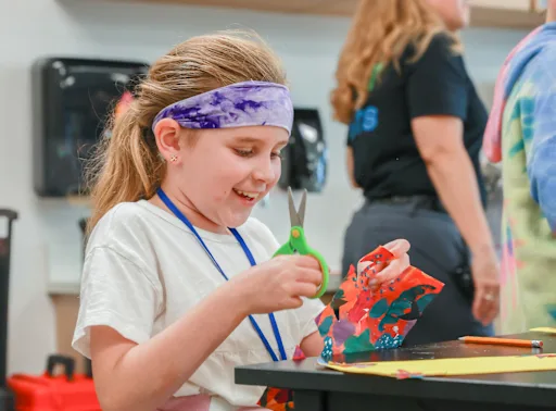 young student cutting paper with scissors