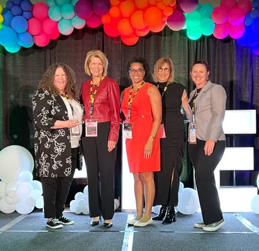 group of women smiling under balloon arch