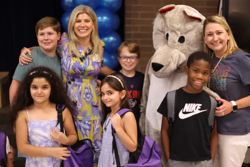 teachers and young students posing with a wolf mascot