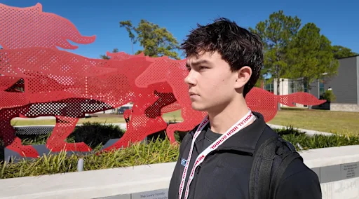 Evren Meyers standing in front of mustang statue at memorial high school