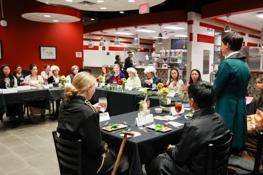 students in historical clothing sat around banquet table