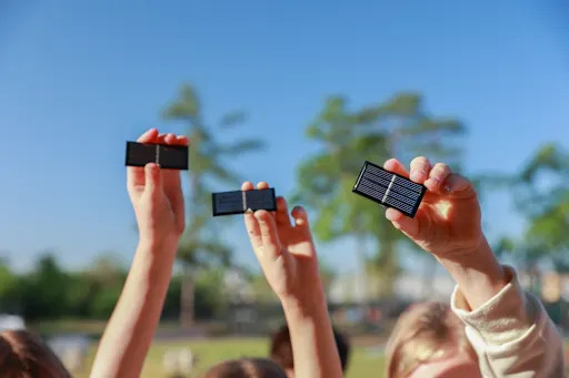 students holding small solar panels to the sky