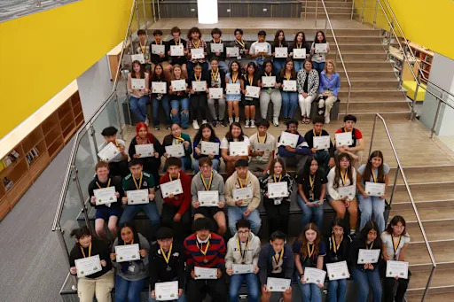 students sitting on a stairwell holding certificates