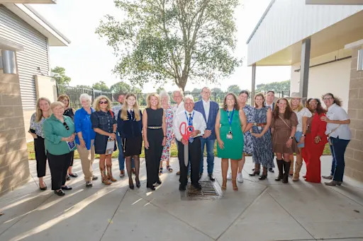 group of people holding ceremonial robbon-cutting scissors in front of new agricultural science center