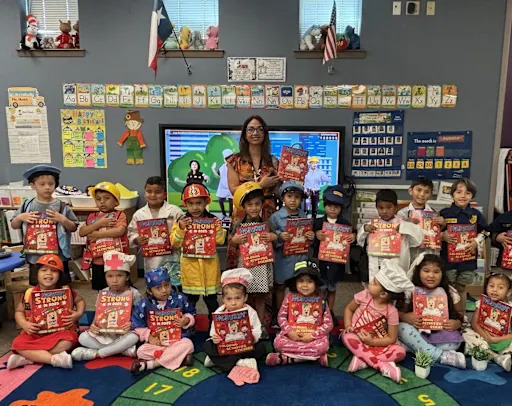 students holding books featuring H-E-B's mascot
