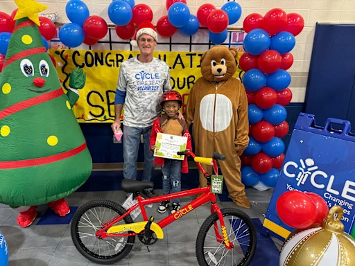 student with bear mascot behind a bike