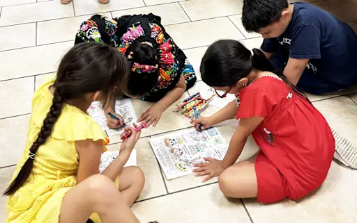 young students working on coloring sheets on the floor