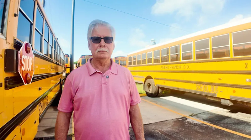 Richard Hyland standing among school busses