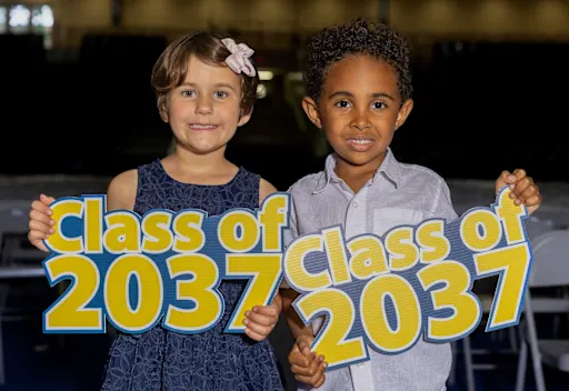 Two young students holding signs reading "Class of 2037"