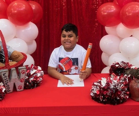 young student smiling with large pencil