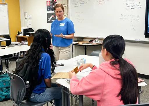 teacher helping two students at a table
