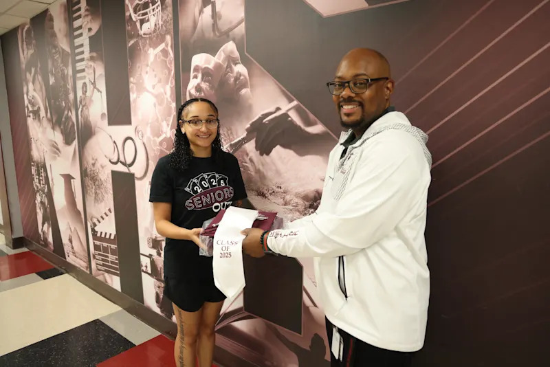 Principal HP Hyder III handing La'Nyah Davis folded graduation attire