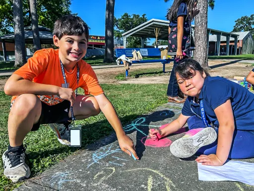 Two children drawing with chalk on the sidewalk