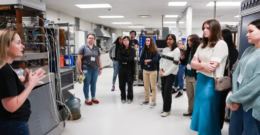 group of students listening to a woman teaching them