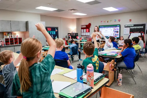 Meadowwood Elementary students raising their hands in class