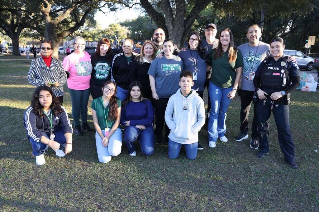A group of people, including two in law enforcement uniforms, poses for a photo outdoors.