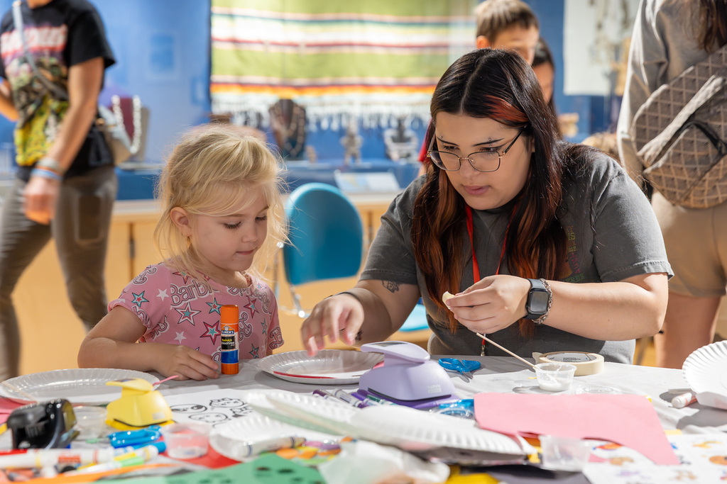 Woman and child sitting at a table with art supplies in front of them.