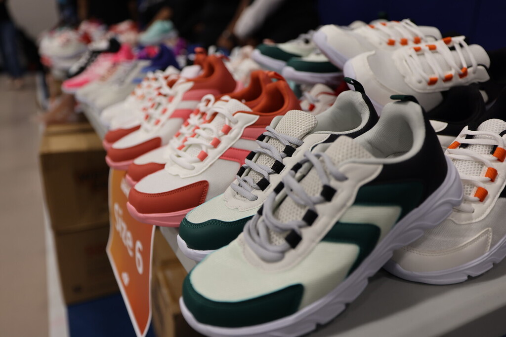 A display of various sneakers, including white, red, green, and orange, arranged on a table.
