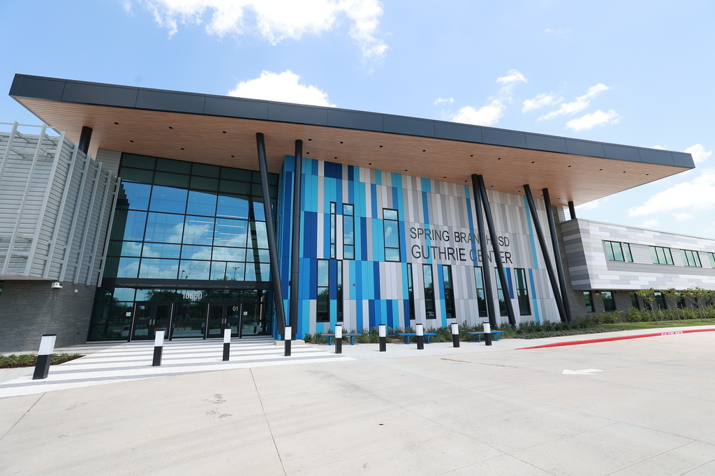 Exterior of a modern building with blue and white stripes, glass windows, and a gray roof.