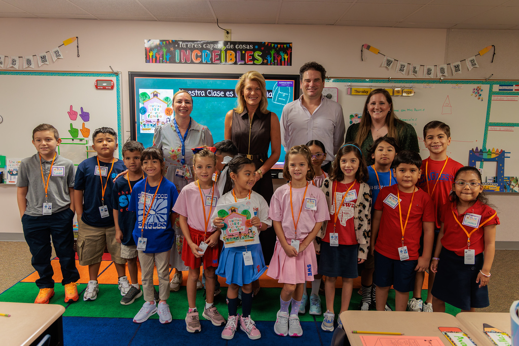 A group of children in uniforms, ID cards around their necks, posing in a classroom.
