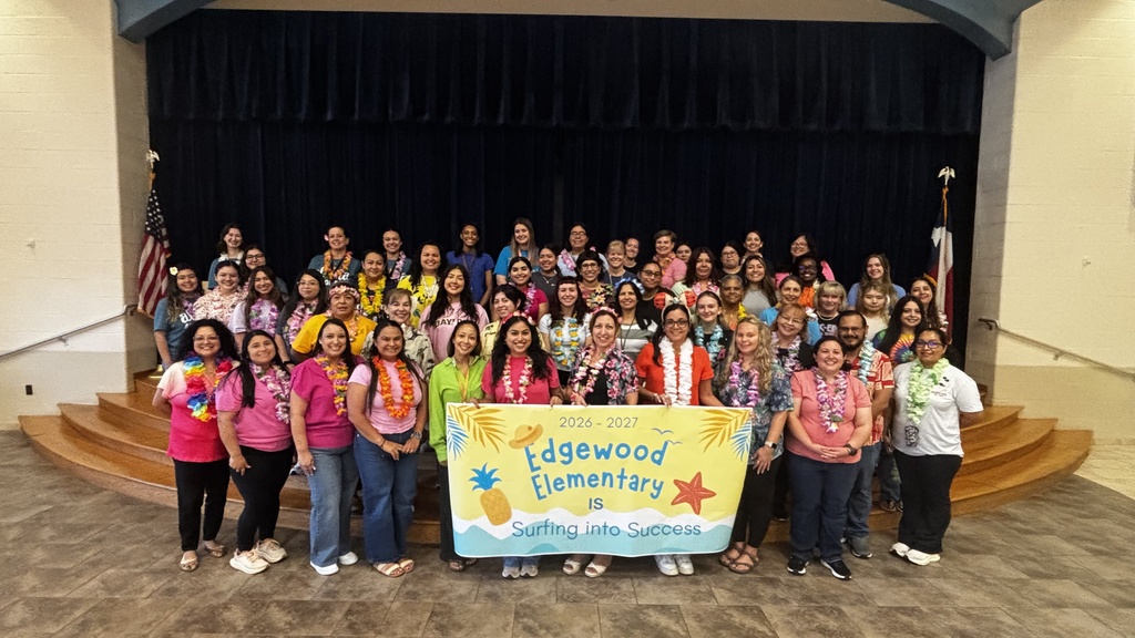 A group of people stands in front of a stage with a banner reading "Edgewood Elementary" is Surfing into Success!