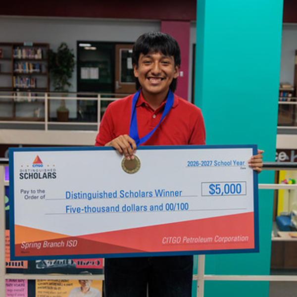 Person holds a large check for $5,000. Person wears a medal and a red shirt.