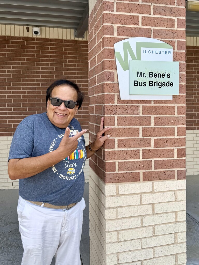 Bus driver recognized for his good work. Standing near naming sign.