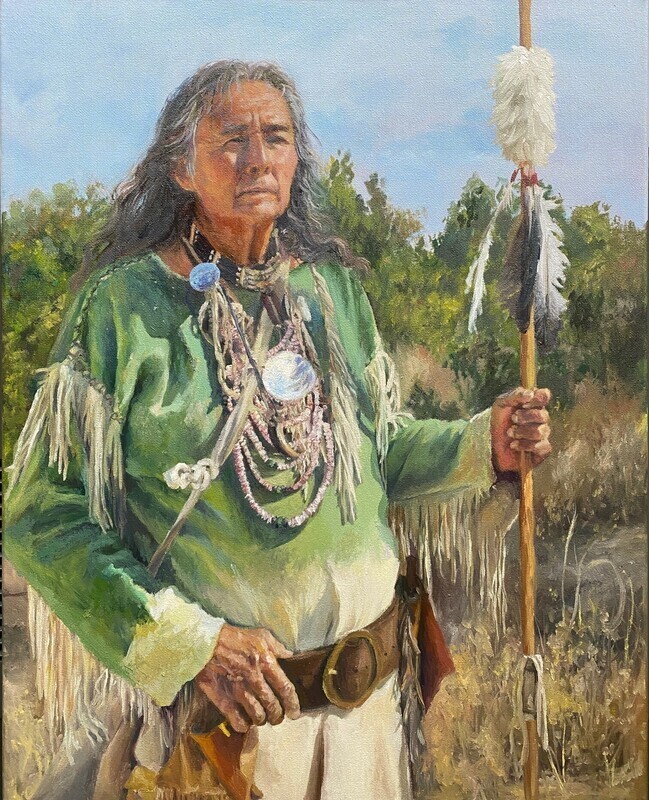 A person in traditional attire, holding a spear with a feather, stands in a field. Background includes trees.