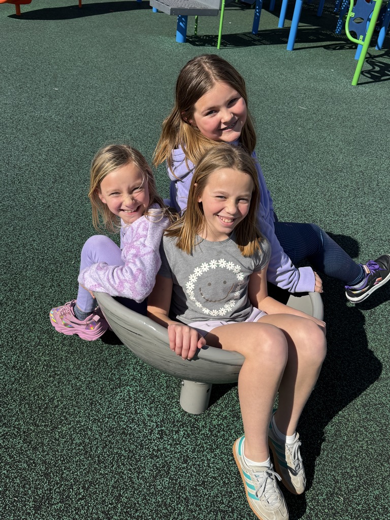 Girls outside on the wobble chair on the playground
