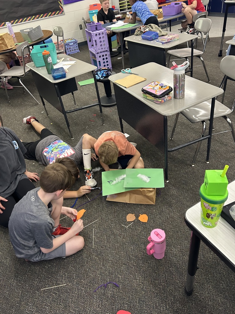 Students working in groups to build a house out of construction paper.