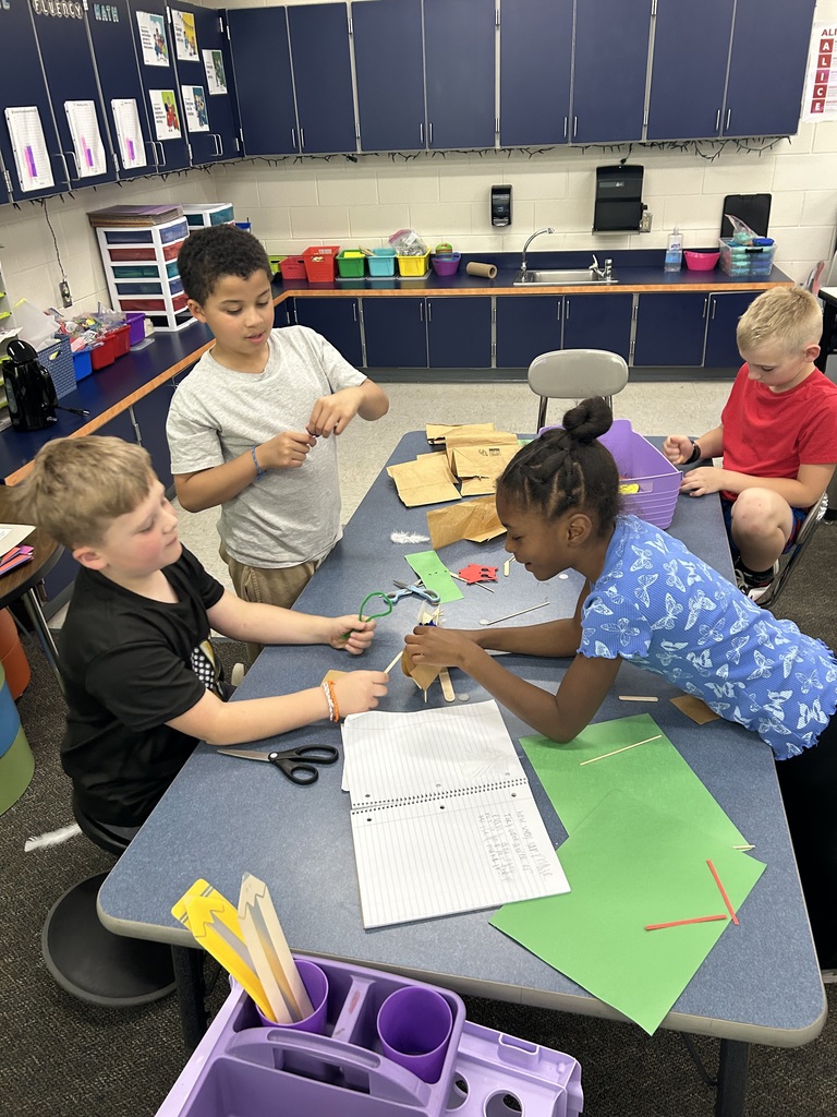Students work together to build a house out of construction paper.