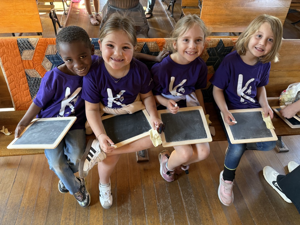 Kindergarten students siting in an old school house.