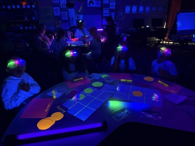 Students reading with black light and fluorescent light around them 