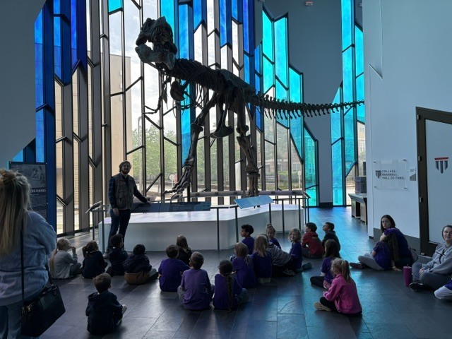 Students looking at a skeleton of a T-Rex dinosaur.