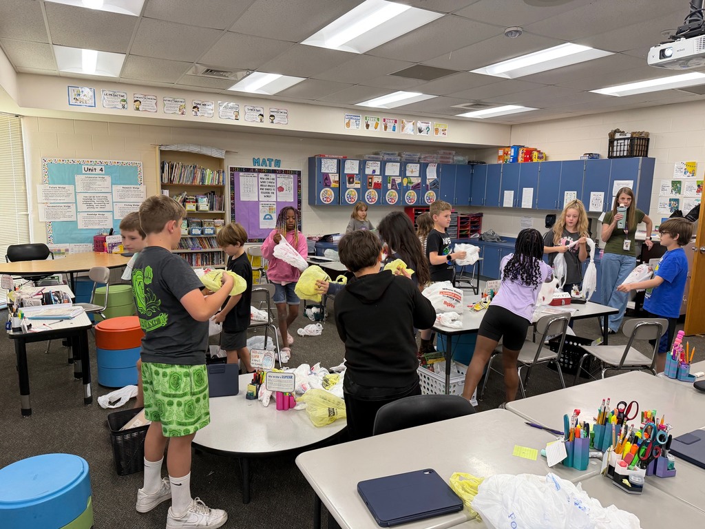Students linking together grocery bags to make sleeping mats for the homeless.
