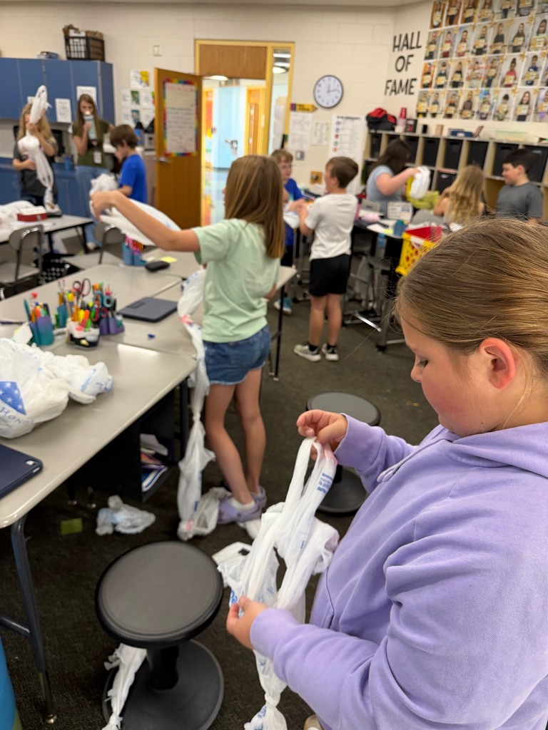 Students linking together grocery bags to make sleeping mats for the homeless.
