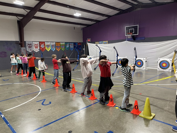 Students lined up and firing bows and arrows